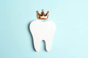 Tooth in the crown on a blue background. Happy Dentist's Day concept.